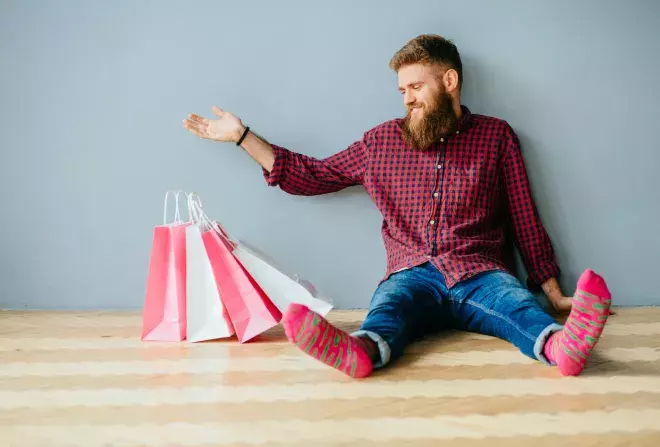 man in socks sitting with shopping bags