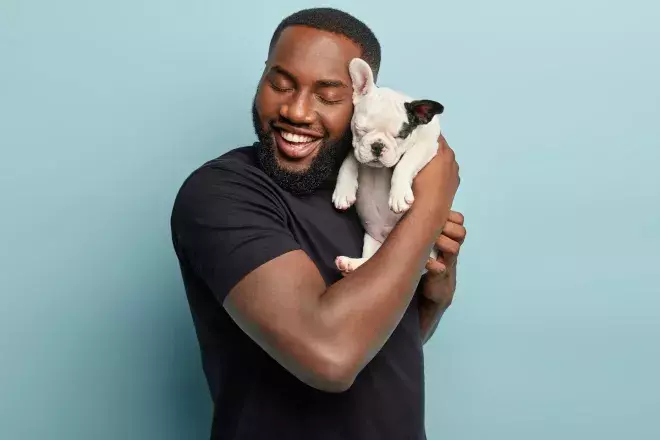 man happily squeezing puppy
