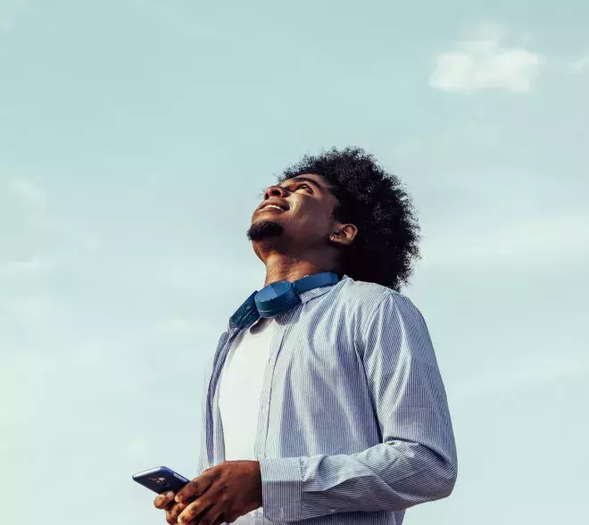 person holding cell phone looking up to the clouds