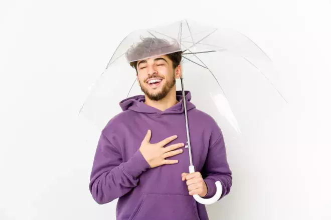 man holding umbrella with relieved expression