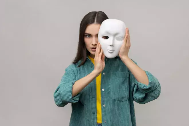woman holding white blank face mask slightly over her face