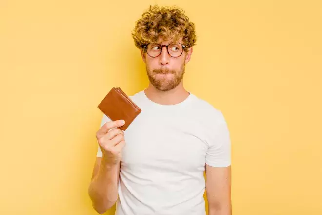 concerned man holding up wallet