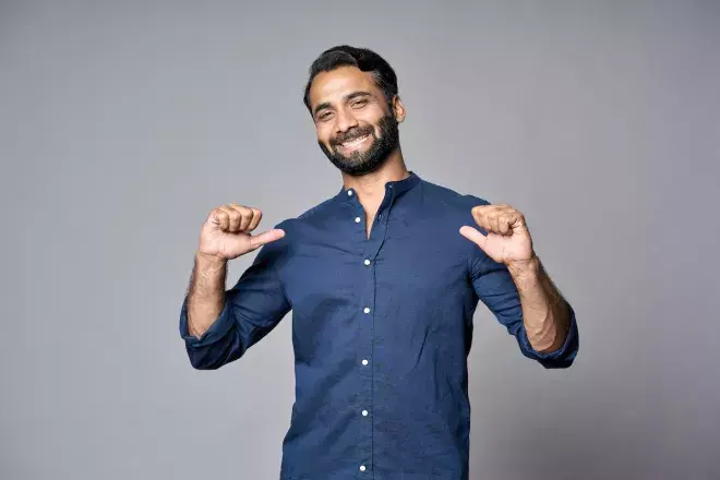 confident person smiling and pointing at self