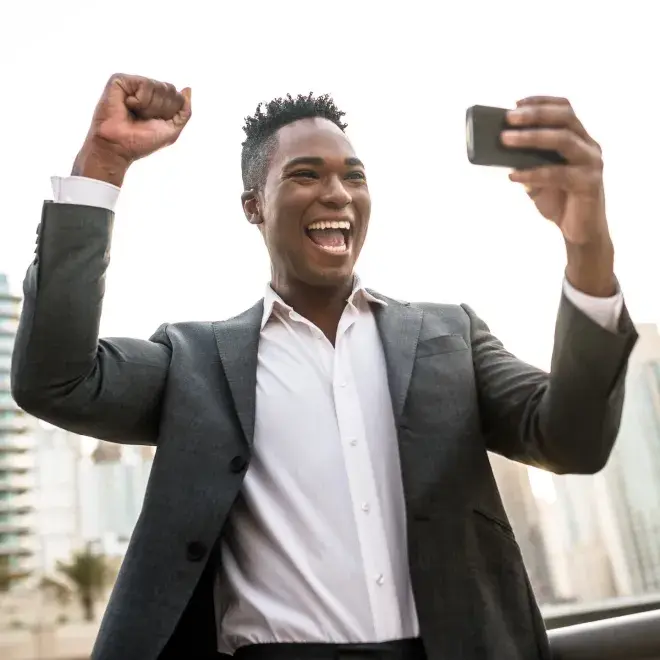 business man smiling and cheering holding phone