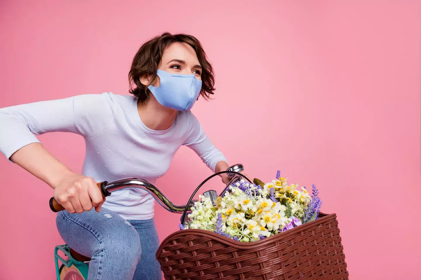 happy woman wearing face mask riding bike collecting flowers
