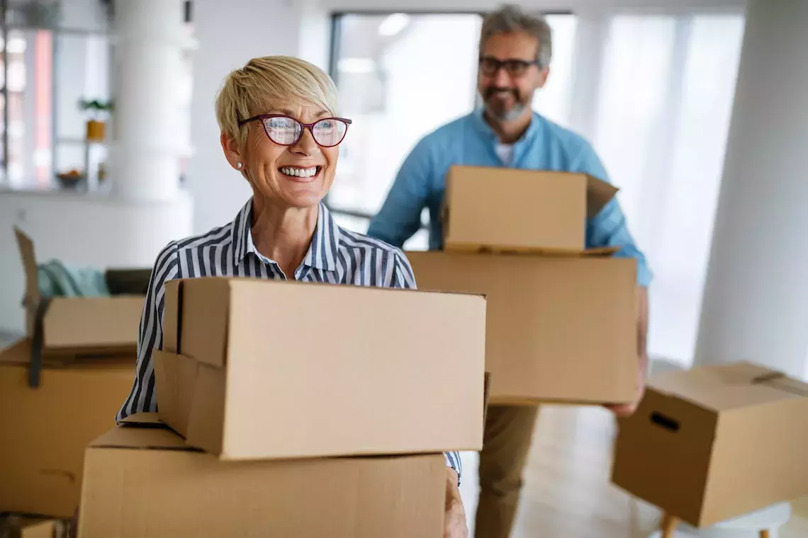 elderly couple moving boxes into new home