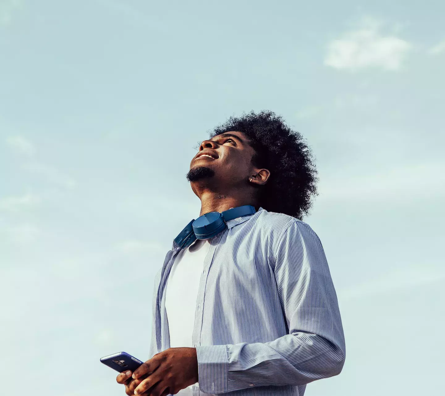 person holding cell phone looking up to the clouds