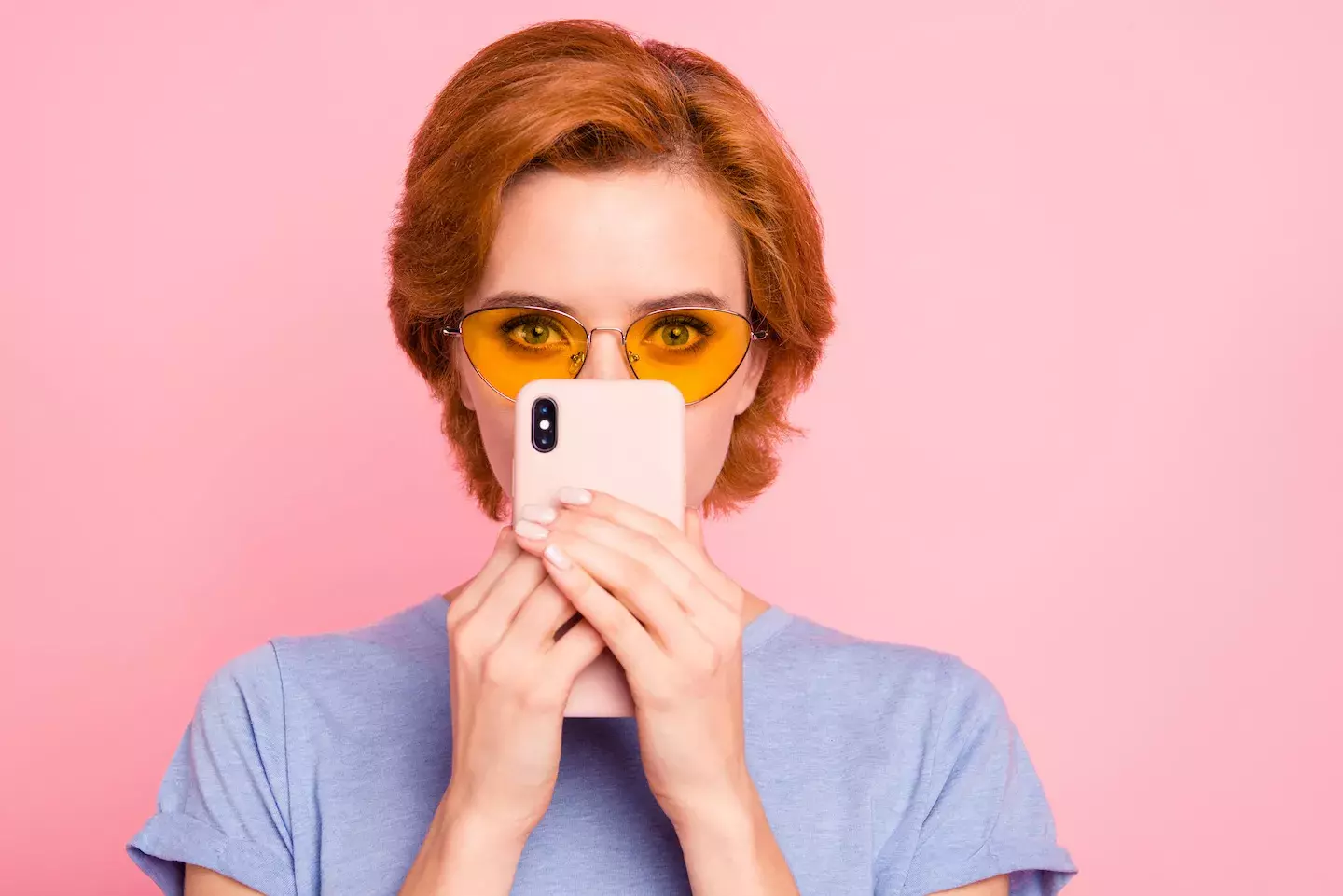 Suspicious person wearing glasses hiding behind cell phone