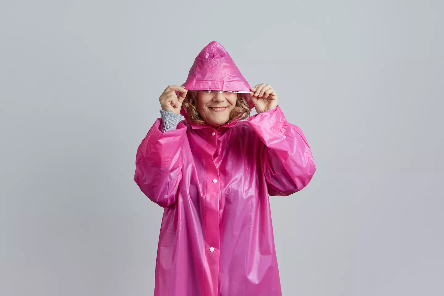 person hiding in raincoat pulling hood over face