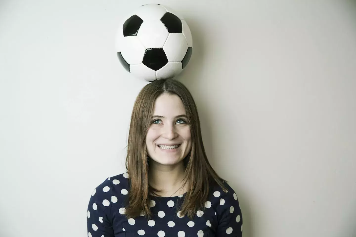 woman smiling balancing soccer ball on head