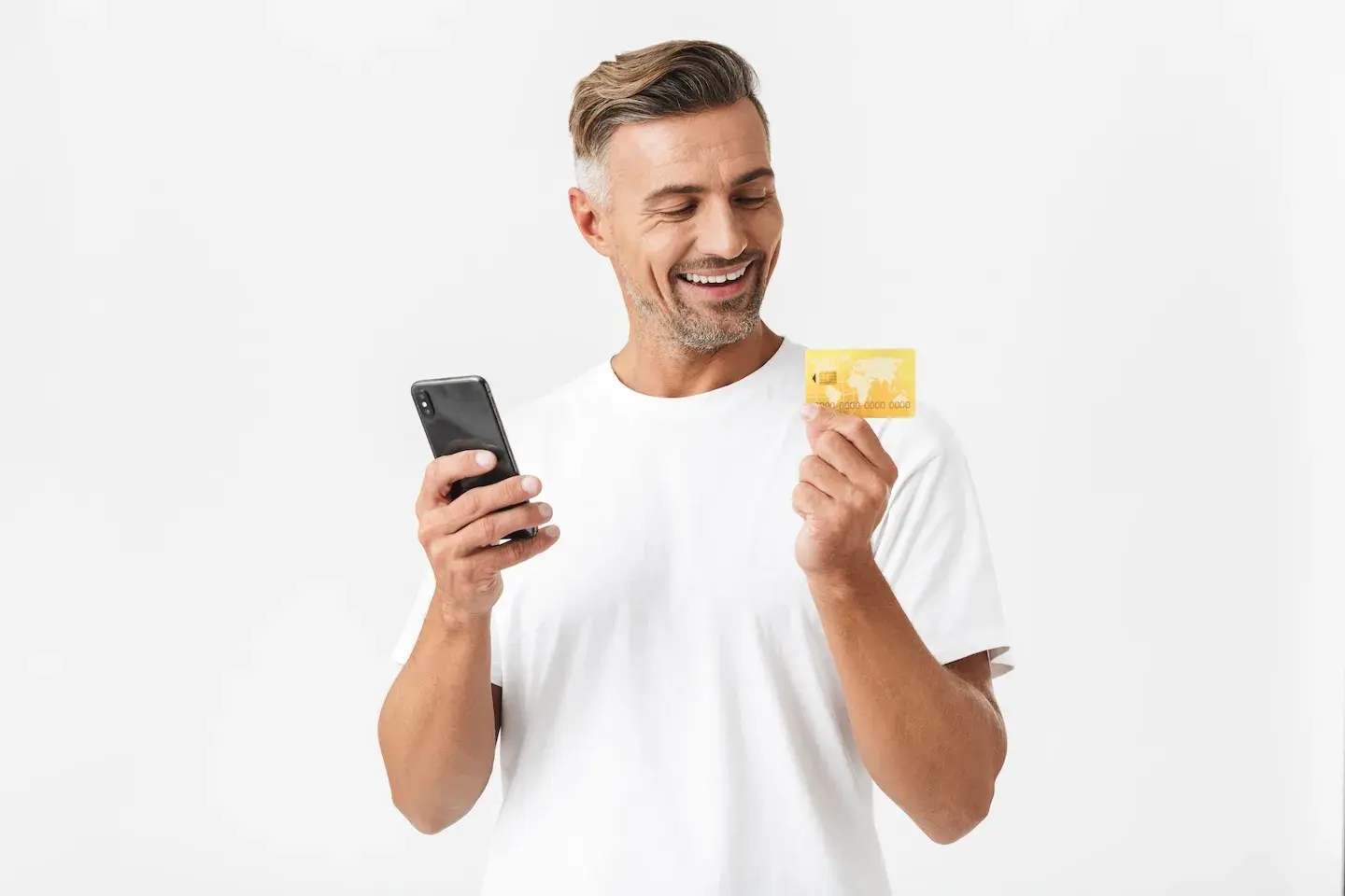 man smiling looking at credit card and holding phone
