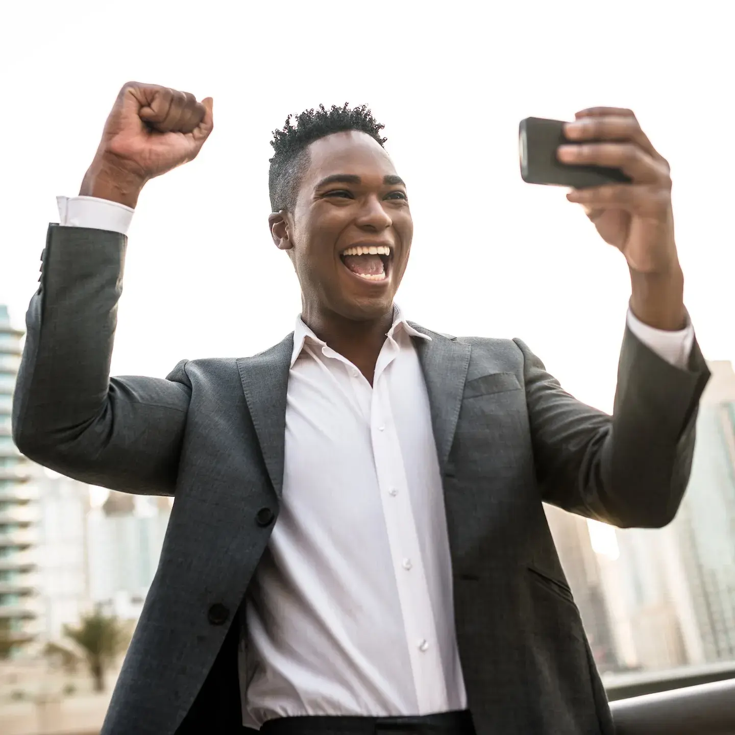 business man smiling and cheering holding phone