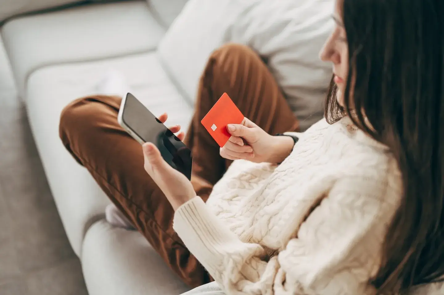 woman looking down at phone with credit card in hand