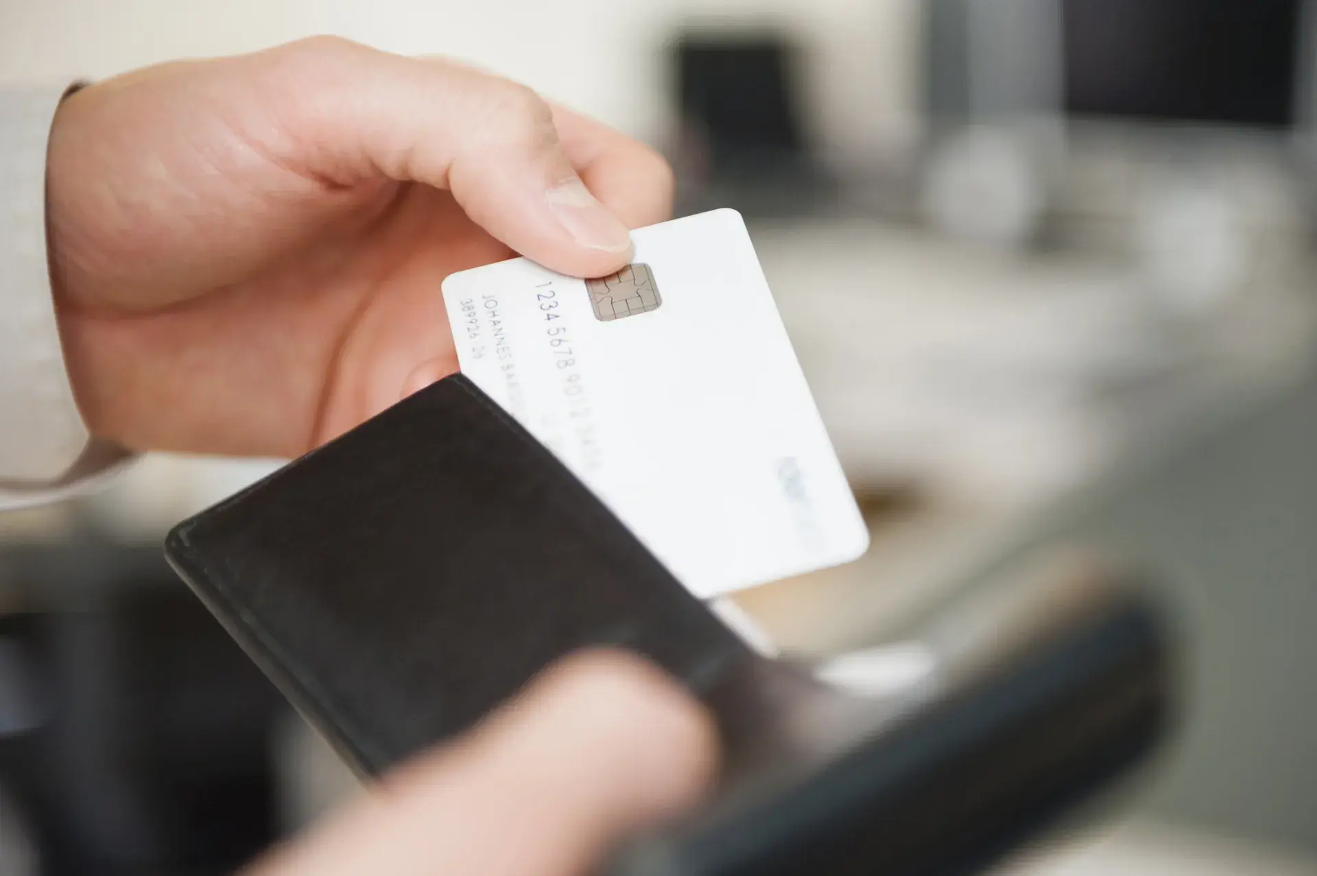 a hand holding a credit card coming out of a wallet