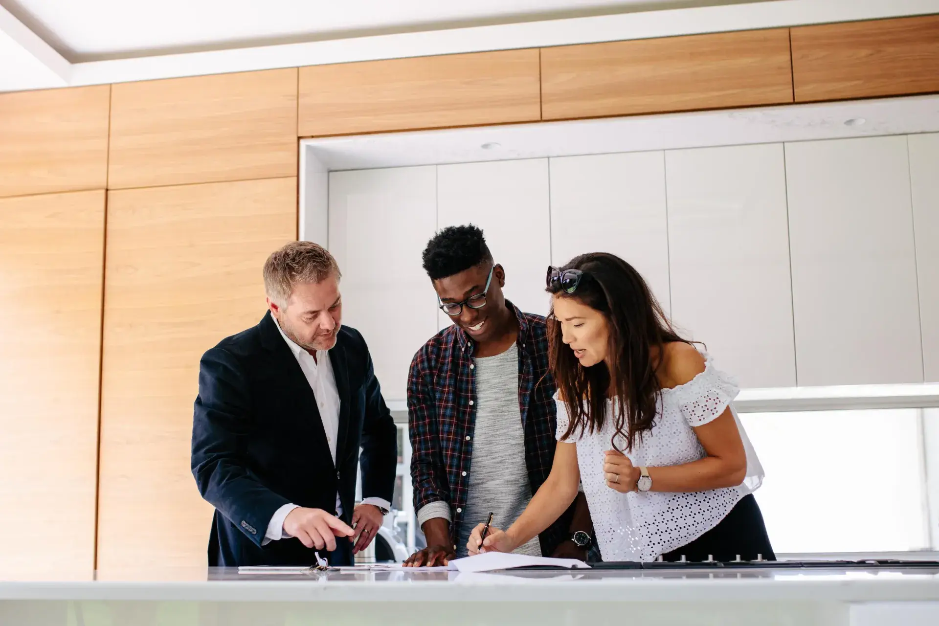 Couple leaning over counter with real estate agent, signing document